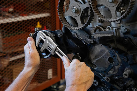 Mechanic using 11 inch automotive wrench with big jaw capacity and slim head on engine, smooth jaws protecting fittings.