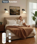HOJOYRI Black Recharge Battery Operated Wall Sconces Set of Two with Remote above a bed, providing warm light in a cozy bedroom.