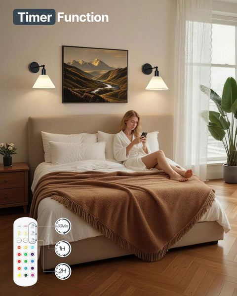 HOJOYRI Black Recharge Battery Operated Wall Sconces Set of Two with Remote above a bed, providing warm light in a cozy bedroom.