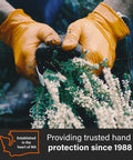 Gloveworks orange nitrile work gloves with raised diamond grip; close-up of hands gripping plant stems.