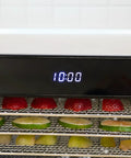 Top Shelf Eight Tray Stainless Steel Food Dehydrator Running Smooth With Digital Timer And Adjustable Temp Control Made For Killer Jerky Dried Fruits Veggies Fresh Herbs Dog Biscuits 650W Bpa Free showing strawberries and limes drying with timer display.