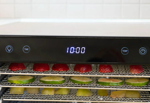 Top Shelf Eight Tray Stainless Steel Food Dehydrator Running Smooth With Digital Timer And Adjustable Temp Control Made For Killer Jerky Dried Fruits Veggies Fresh Herbs Dog Biscuits 650W Bpa Free showing strawberries and limes drying with timer display.