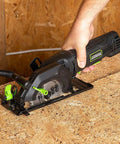 Genesis Mini Circular Saw 4.0 Amp 4-1/2 Inch with 24-Tooth Carbide Blade cutting wood surface with vacuum adapter attached