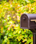 Roxbury Weather Resistant Steel Mailbox With Post Rubbed Bronze Finish Medium Curbside Mailbox With Magnetic Latch USPS Approved in garden setting