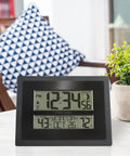 Digital Atomic Clock With Outdoor Temperature And Moon Phase Auto Time Sync Large Two Inch Digits Twelve Or Twenty Four Hour Display DST Auto Seven Time Zones No Fuss Setup Black Wall Or Desk Clock For Home And Office on white table with plant