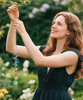 Seven Piece Crystal Gazing Ball Spiral Wind Spinner Suncatchers For Garden Decor, Durable Metal Frame With K9 Crystal Prisms, Cool Colorful Outdoor Yard Ornaments That Catch Sunlight And Spin In The Breeze, hanging by a woman in a garden