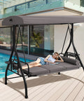 Woman relaxing on a Three Seat Patio Swing With Adjustable Canopy And Stand Heavy Duty Outdoor Porch Glider Bench With Cushions Pillows And Cup Holder For Backyard Garden Lawn Poolside Gray by a poolside.