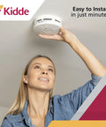 Woman installing 2-In-1 Smoke And Carbon Monoxide Detector Combo With 10 Year Battery For Whole Home Safety White Featuring Photoelectric And Electrochemical Sensors For Fast Reliable Alerts And Peace Of Mind.