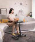 Woman using Height Adjustable Laptop Rolling Cart for Ergonomic Workstation Use, Mobile Desk from 28 Inches to 33 Inches, Black Finish.
