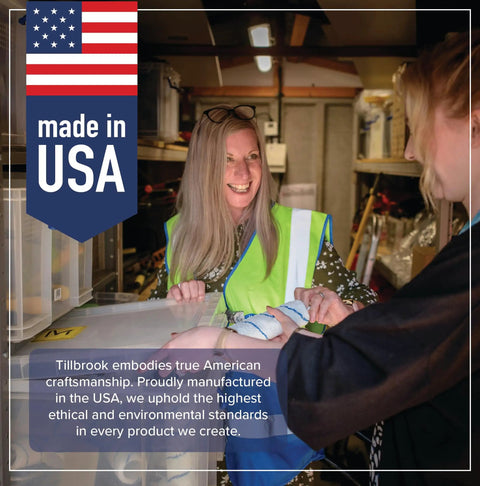 Two people in a workshop setting, one wearing a safety vest, smiling and interacting near a 'Made in USA' sign.