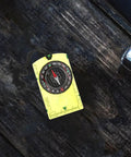 Portable Acrylic Hiking Compass For Outdoor Camping And Backpacking on dark wood surface, precise navigation tool