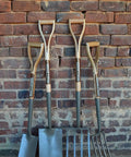 Heritage Forged Digging Fork With Solid Carbon Steel Head And Wishbone Handle 28 Inch Weatherproof Hardwood Shaft displayed with spades
