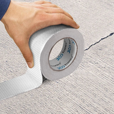 Person applying Heavy Duty Waterproof Butyl Sealing Tape With Aluminum Foil Backing For RV Roofs And Gutters on a cracked surface