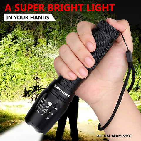 Hand holding Beefy 3000 Lumens Small LED Flashlights 4 Pack With 5 Modes Zoomable Water Resistant All Weather, beam on trees