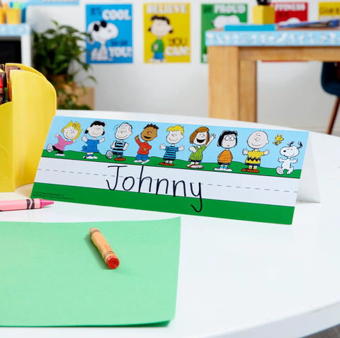 Peanuts Themed Tented Nameplates For Student Desks, 9.5 By 6.5 Inches, with cartoon characters shown on a classroom desk.