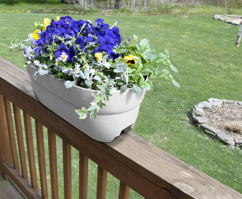 Railing Planter With Drainage Holes For Decks And Balconies 24 Inch Weatherproof Resin Planter Made From Polyethylene Plastic In White Fits Wood Or Metal Rails Ranging 1.25 To 3.875 Inches Wide installed on a deck railing with flowers