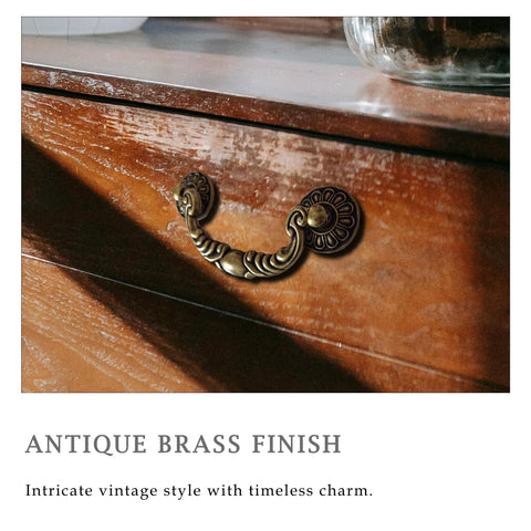 Vintage drop bail cabinet handle in antique brass finish on wooden dresser, showcasing intricate design and timeless style.