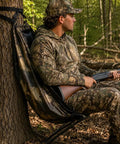Hunter sitting in Low Profile Hunting Chair Hammock Seat With 360 Degree Swivel Portable Camouflage Ground Stool For Deer And Turkey.