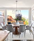 Whitney 27 Inch 5 Light Modern Farmhouse Chandelier With Conic Clear Glass Shades in dining room with light grey chairs.