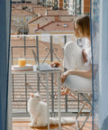 Woman on balcony with cat, using Balcony Pet Net For Cats And Dogs, 16.5 Ft By 2.5 Ft Anti Fall Mesh Fence Netting for safety.