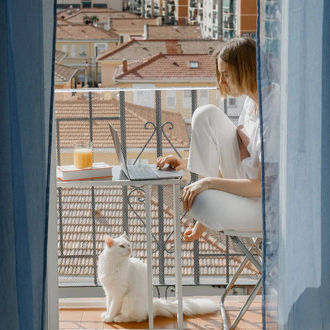 Woman on balcony with cat, using Balcony Pet Net For Cats And Dogs, 16.5 Ft By 2.5 Ft Anti Fall Mesh Fence Netting for safety.