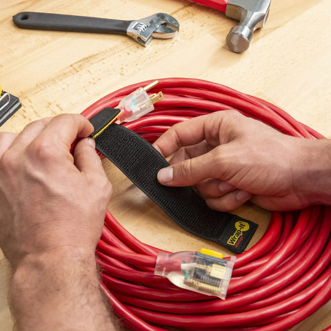 Hands using Selfie Straps 12 Inch 8 Pack Black Super Handy Stretchy Hook and Loop Cord Organizer on red electrical cable.