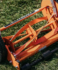 Close-up of 1204-14 14-Inch 4-Blade Push Reel Lawn Mower blades and wheels, red finish, on grass, lightweight 19-pound body, no gas needed.