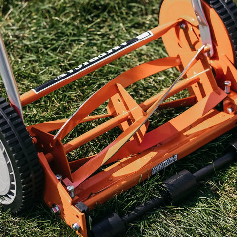 Close-up of 1204-14 14-Inch 4-Blade Push Reel Lawn Mower blades and wheels, red finish, on grass, lightweight 19-pound body, no gas needed.