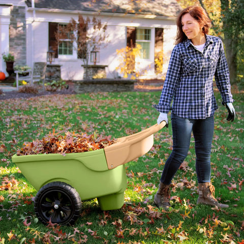 Person using Easy Haul Wheelbarrow Green Garden Cart for yard work with wide wheel and durable steel frame in autumn setting.