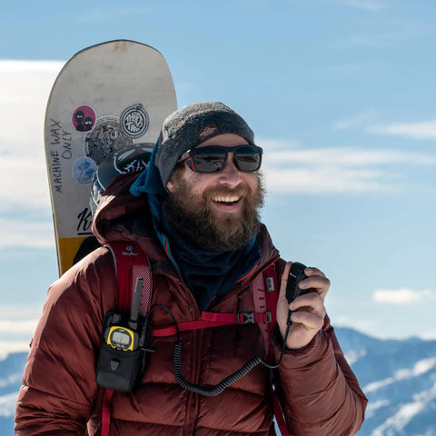 Man using Push To Talk Handheld And Wearable Speaker Microphone Set For GMRS Radios, snowy mountains in background