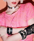 Woman wearing pink lace top with spiked leather bracelets, showcasing 455 Piece Punk Studs Kit For Clothing And Accessories With Metal Spikes And Leather Rivets DIY Punk Style Decoration Clothes Shoes Belts And Dog Collars Includes Cone And Pyramid Studs Round Dome Rivets With Puncher Awl Screwdriver And Storage Box.