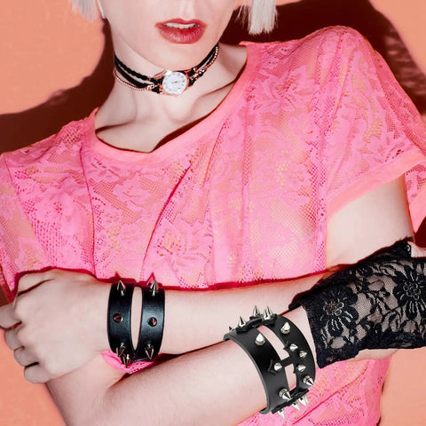 Woman wearing pink lace top with spiked leather bracelets, showcasing 455 Piece Punk Studs Kit For Clothing And Accessories With Metal Spikes And Leather Rivets DIY Punk Style Decoration Clothes Shoes Belts And Dog Collars Includes Cone And Pyramid Studs Round Dome Rivets With Puncher Awl Screwdriver And Storage Box.