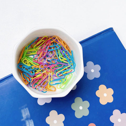 Ceramic Paper Clip Holder With Gold Line Dispenser on blue floral background, filled with colorful paper clips, office desk organizer