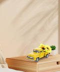 Yellow Metal Truck Decor With Artificial Sunflowers on wooden tabletop, cozy farmhouse charm for home accent and seasonal display.