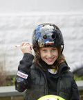Child wearing Dry Erase Kids Helmet For Bike, Skate, Scooter And Inline Skating With Neon Markers And Stencil Kit, customizing design.