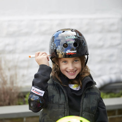 Child wearing Dry Erase Kids Helmet For Bike, Skate, Scooter And Inline Skating With Neon Markers And Stencil Kit, customizing design.