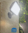 Dusk To Dawn Outdoor 100W LED Flood Light with Knuckle Mount and Wall Plate in rain highlighting waterproof feature.