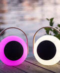 Eye Color Changing LED Lantern With 10W Bluetooth Speaker, pink and white mood lamp on wooden deck by water.