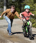 Child on a green 16 Inch Kids Bike For Ages 4 And Up, BMX Style Youth Bicycle With Training Wheels, assisted by an adult.