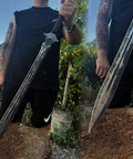 Hand Forged Knight Sword In Spring Steel 35 Inch Full Tang Medieval Blade held by person outdoors, rustic appearance.