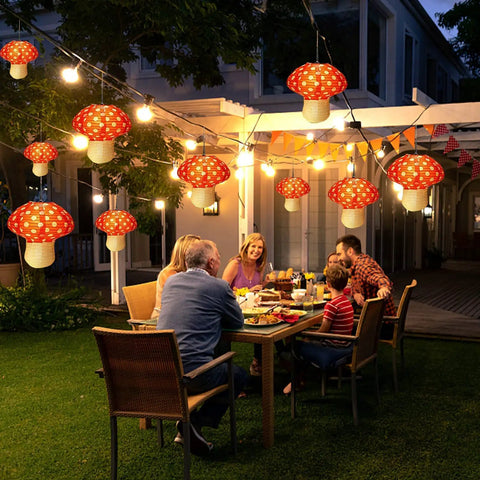 Six Pack Mushroom Paper Lanterns Set For Party Decor And Nursery Ornaments 3D Woodland Mushrooms For Garden Christmas Or Halloween Tables Easy To Assemble And Hang Orange Red Color lighting up an evening garden dinner.