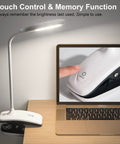 Clip On LED Desk Lamp With Battery Power Cordless Bedside Light Flexible Arm Eye Caring Memory Touch 3 Color Modes And Stepless Brightness Portable Reading Light For Study And Work next to laptop showcasing touch control feature.