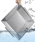 Hand holding stainless steel grill basket under water, highlighting durability. Stainless Steel Grill Basket For Indoor And Outdoor Use Large 12 By 12 By 2 Inch Veggie And Kabob Grilling Basket Heavy Duty Dishwasher Safe For All Grills Grill Like A Boss For All Skill Levels.