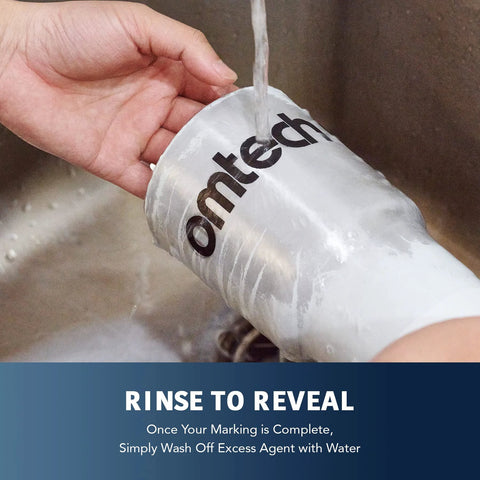 OMTech laser marking spray aerosol can, white 13 oz with OMTech logo, being rinsed under running water.