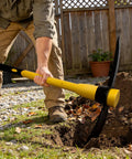 Person using Heavy Duty Forged Steel Pick Axe With Shock Absorbing Fiberglass Handle For Digging And Chiseling In Hard Ground Concrete And Rocky Soil 36 Inch Length For Maximum Leverage And Reduced Vibration 406Y in garden