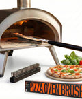 26 Inch Pizza Oven Brush With Stone Scraper Set Includes Two Brush Heads Heat Resistant Stainless Steel Bristles Long Grip Handle Go To Pro Grade Tool For Pizza Stones Compatible With Ooni Gozney Blackstone Solo Stove Ovens in use cleaning a pizza stone next to fresh pizza and packaging.