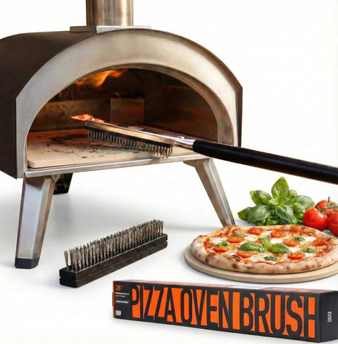 26 Inch Pizza Oven Brush With Stone Scraper Set Includes Two Brush Heads Heat Resistant Stainless Steel Bristles Long Grip Handle Go To Pro Grade Tool For Pizza Stones Compatible With Ooni Gozney Blackstone Solo Stove Ovens in use cleaning a pizza stone next to fresh pizza and packaging.
