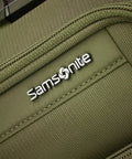 Close-up of Lineate Softside Expandable Go To Carry On Luggage With Spinner Wheels Cedar Green's front fabric texture and logo.