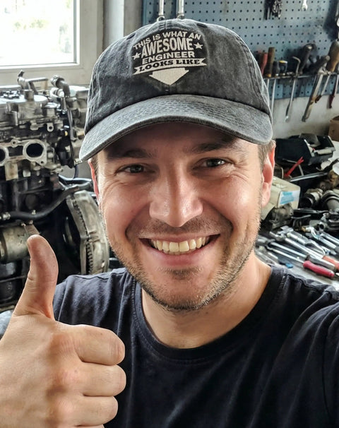 Adjustable Vintage Washed Cotton Embroidered Cap For Engineers And Mechanics The Ultimate Gift For Mechanical Engineers Men And Women Dark Grey Comfortable Fit Durable Everyday Workwear Hat worn by smiling person in workshop.