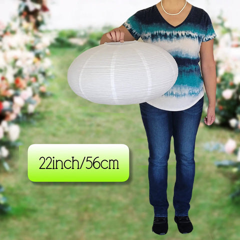 Person holding an Oval Crepe Paper Lanterns 22 Inch Two Pack For Indoor Ceiling Decor in a garden setting